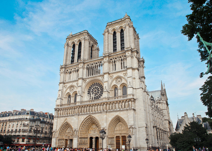 Crkve Notre Dame s dva tornja, plavo nebo u pozadini i ljudi u okolici.