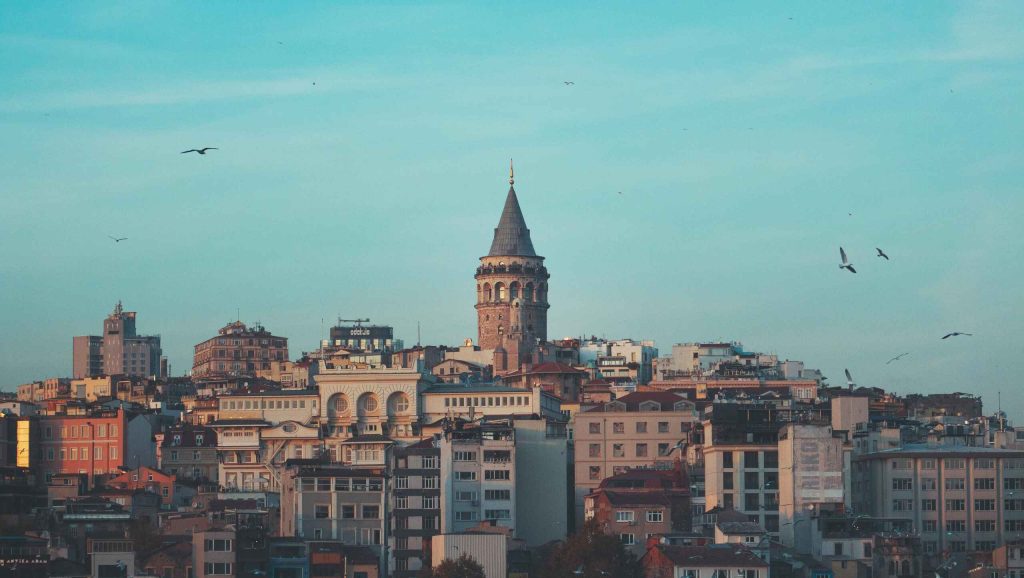 Galata Toranj i zgrade u kvartu Karakoy u Istanbulu, plavo nebo i ptice u pozadini