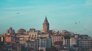Gdje odsjesti u Istanbulu? Galata Toranj i zgrade u kvartu Karakoy u Istanbulu, plavo nebo i ptice u pozadini