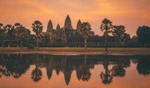 Kambodža: kako posjetiti Angkor Wat? Angkor Wat zalazak sunca, odsjaj tornjeva u vodi i nebo narančaste boje.
