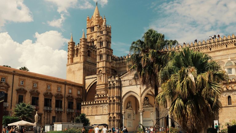 Katedrala u Palermu sa palmama u dvorištu i zelenim palmama.