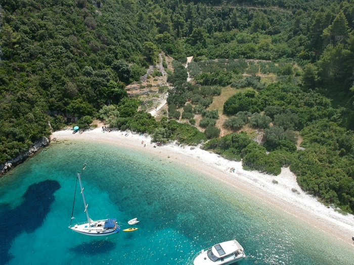 Plaža s kamenčićima, plavo more i brodovi