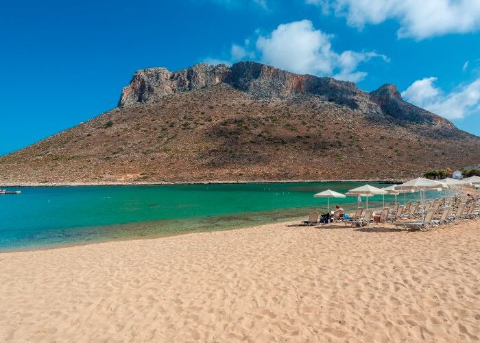 Tirkizna plaža sa planinom u pozadini.