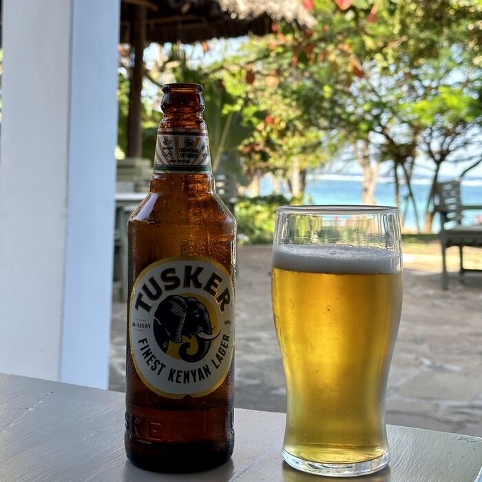 A bottle of Tusker Beer on the beach.