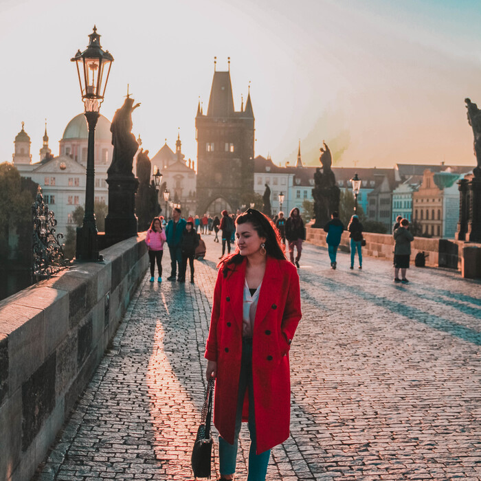 Ana in the morning on Charles Bridge with golden light falling down.
