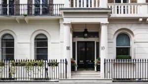 Tipična kuća u Londonu s bijelom fasadom i crnim vratima.