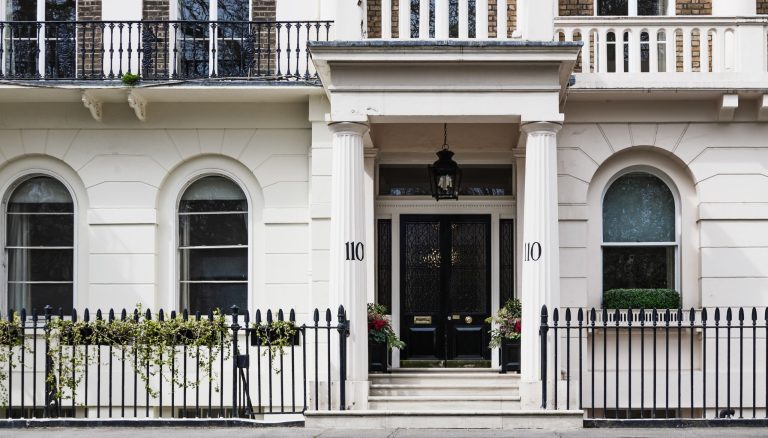 Tipična kuća u Londonu s bijelom fasadom i crnim vratima.