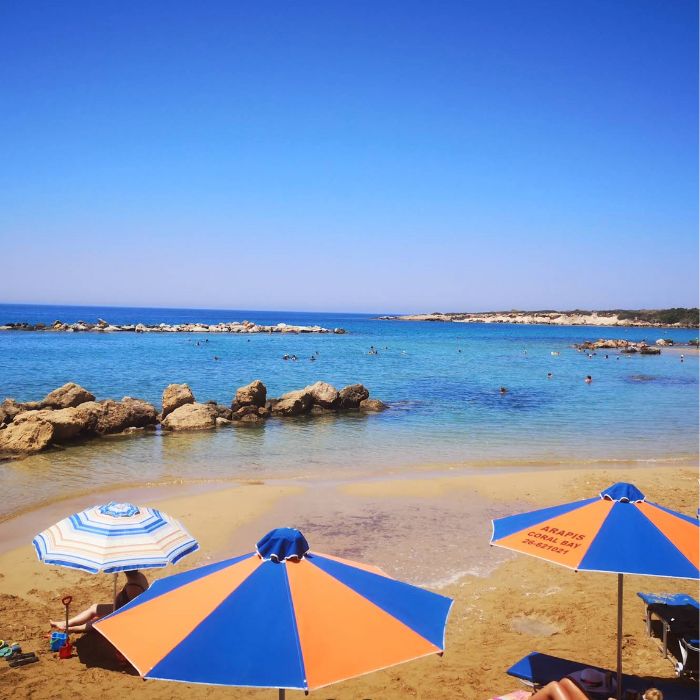 Crveno-natančasti suncobran, plaža i plavo more