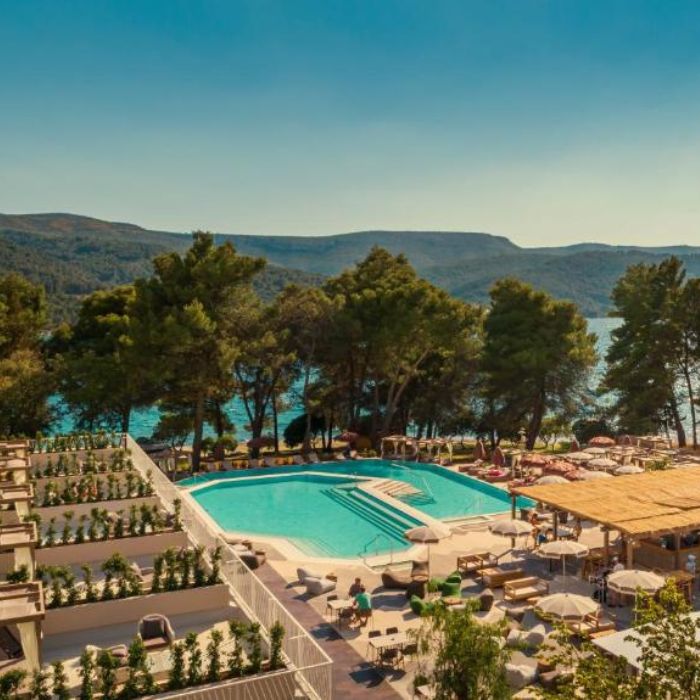 Bazen i ležaljke okruženi čempresima, plavo nebo