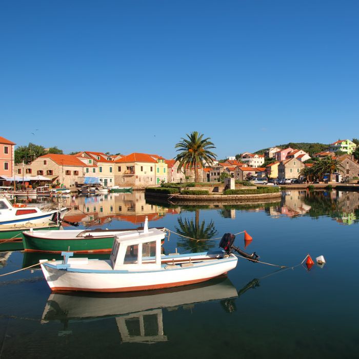 Bijela barka i palma na malom otočiću u uvali