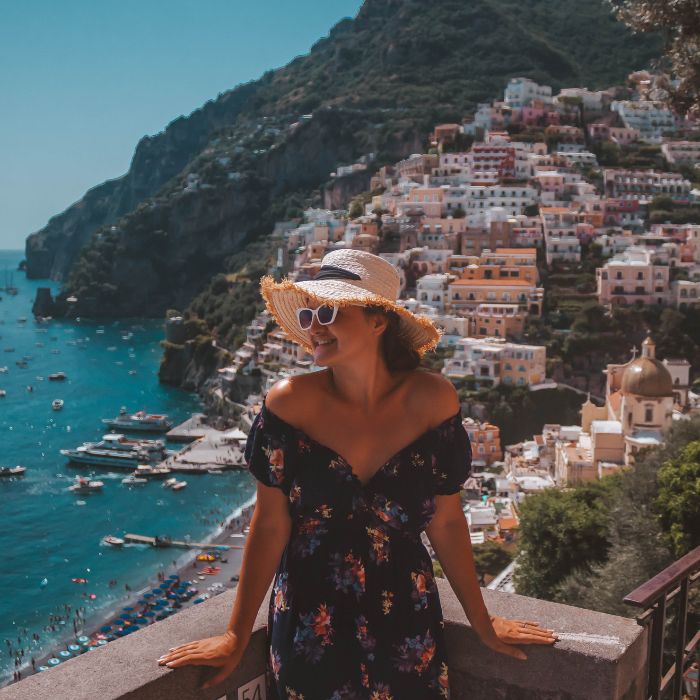 Ana sa šeširom, u pozadini brdo, šarene kuće i more u Positanu