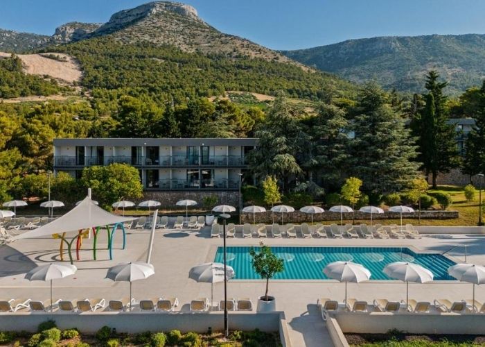 Bazen, ležaljke, suncobrani i pirroda u pozadini