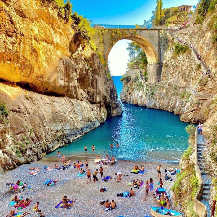 Plaža u uskoj uvali, kupaći i kameni most iznad