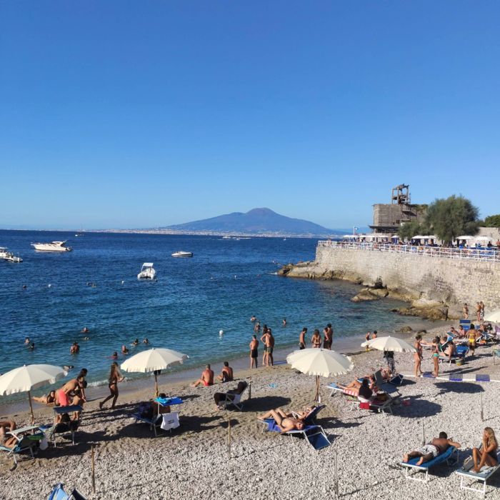 Plaža s kamenčićima, kupaći i pogled na Vezuv