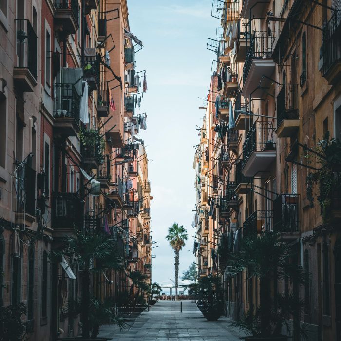 Uska ulica izmedju dvije zgrade, puno malih balkon i na kraju palma i more