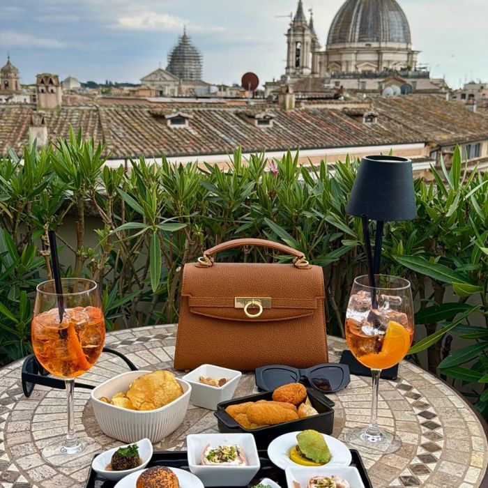 Aperol, torba, suppli i finger food na stolu, u pozadini krovovi Rima