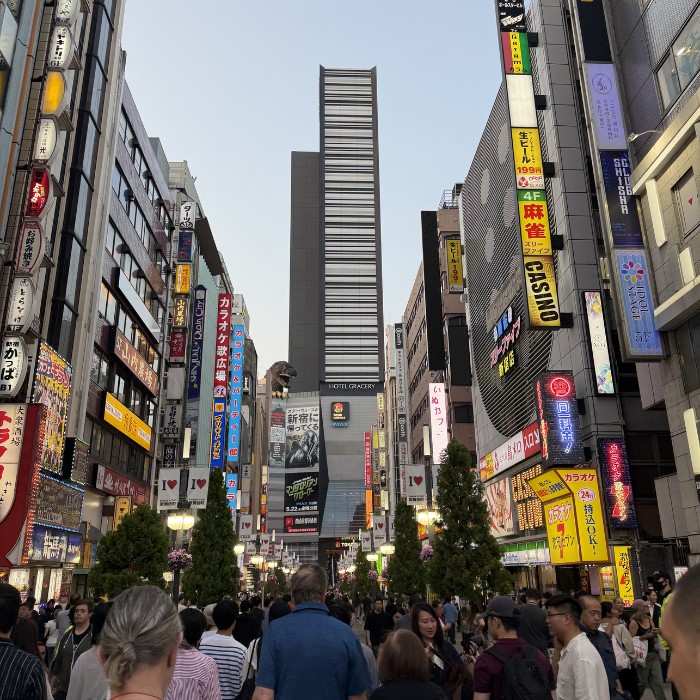 Shinjuku, hrpa ljudi, visoke zgrade, reklame i glava od Godzille