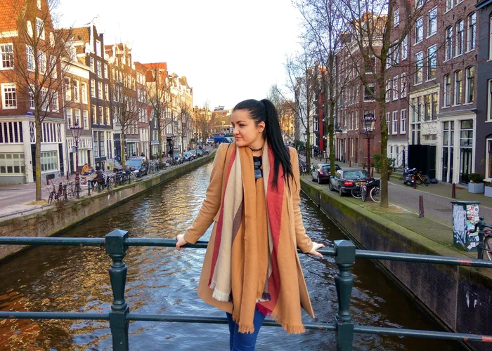 Ana stoji na mostu iznad kanala okruženog kućama u Amsterdamu.
