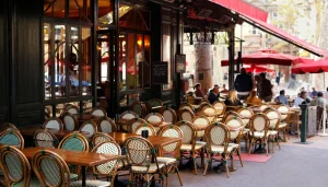 Terasa pariškog restorana s pletenim stolicama, drvenim stolovima i crvenim tendama.
