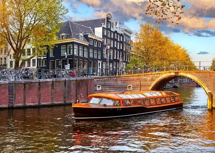 Turistički brod prolazi amsterdamskim kanalom ispod mosta.