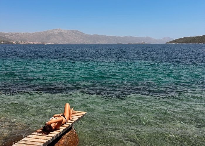 Drveni mol na kojem leži cura, tirkizno more na Zakrjanu Korčula