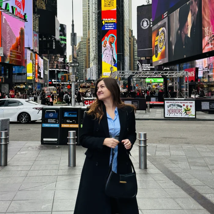 Ana na Times Squareu okružena velikim reklamnim ekranima.