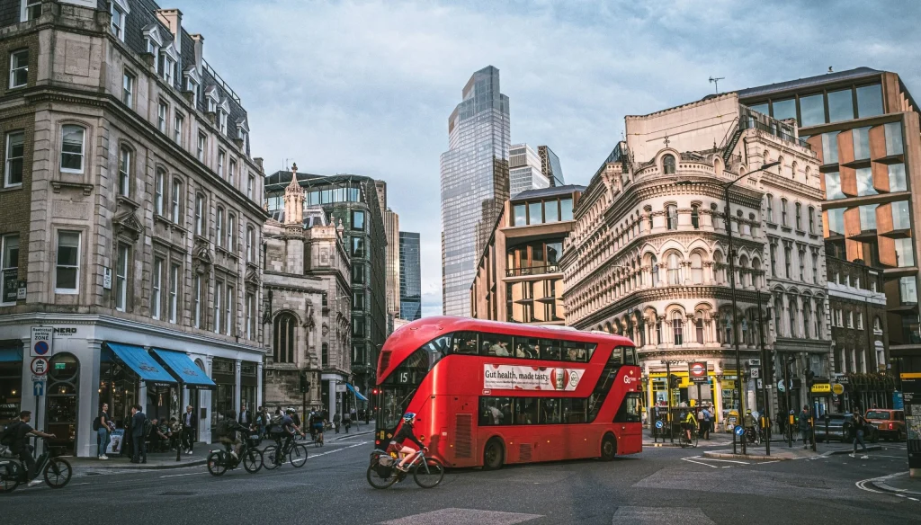Crveni londonski autobus među povijesnim i modernim zgradama.